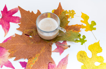 cup of coffee with autumn leaves on white background