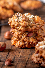 Homemade oatmeal cookies with various nuts and sesame seeds on an old dark wooden table. Tasty and healthy dessert, vegetarian and vegan food. Rustic style. Oatmeal cookies close-up.