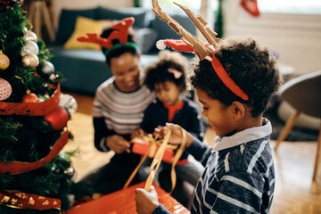 Happy black boy enjoying Christmas preparations with his family at home.