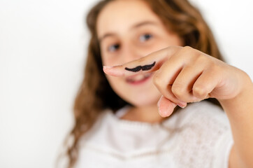 a caucasian girl has a mustache drawn on one finger to celebrate movember