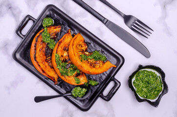 Baked pumpkin slices with green sauce