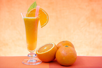 Jugo de naranja y rodaja sobre el vaso, naranjas en la mesa