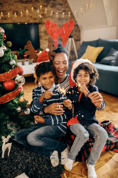 Cheerful black mother and kids having fun while using sparklers on Christmas day,