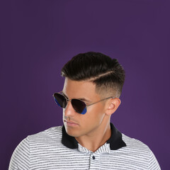 Handsome man wearing sunglasses on purple background, closeup