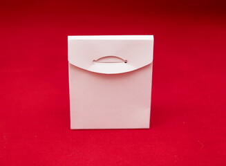 One white cardboard packaging for gifts on red background