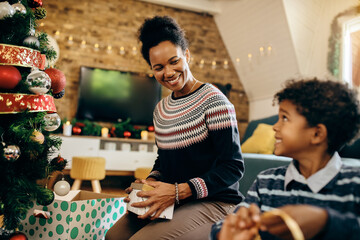 Happy African American mother talking to her son while decorating home for Christmas.