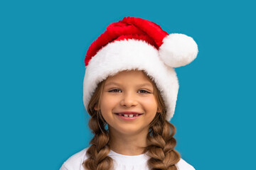 A girl in a Christmas hat poses on a blue background.