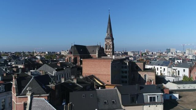Aerial bird view footage of belgian urban cityscape Antwerp city flight towards Sint Norbertuskerk showing typical flemish buildings and architecture crips blue sky background 4k high resolution