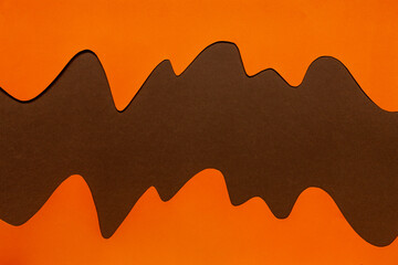 Close up photo of  paper cut decoration pattern frame wavy line from orange and brown paper. Top view, close up..