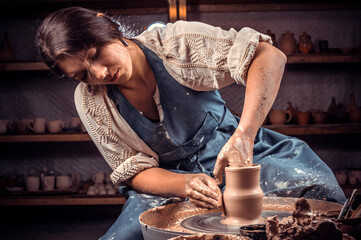 Charming pottery master making ceramic pottery on wheel. Handcraft. - obrazy, fototapety, plakaty