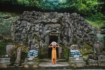 Beautiful girl visiting the goa gajah temple in ubud , Bali - obrazy, fototapety, plakaty