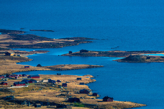 Cabins on the open landscape by a mountain lake in Norway.