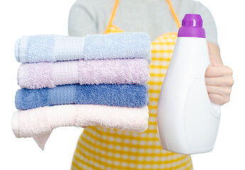 Woman housewife holding bottle liquid detergent gel and stack folded laundry towels in hand on white background isolation