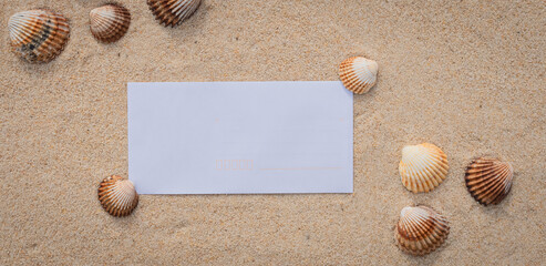 Arrière-plan grains de sable de mer, sable fin de plage avec enveloppe et coquillages. Emplacement pour texte sur papier.