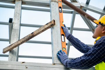 Construction worker measures level wall at window In the house under construction,Level is used to...