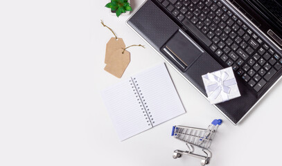 Laptop, note book and shopping trolley on a white background. Online shopping concept