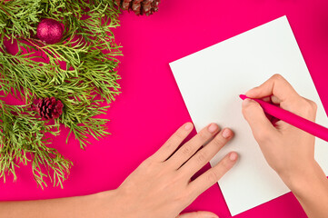 Woman Christmas letter on paper on festive pink background.