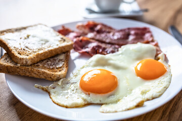Tasty breakfast with two eggs, bacon, toasts and coffee