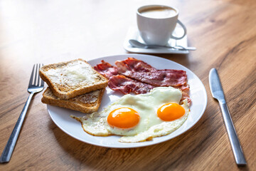 Tasty breakfast with two eggs, bacon, toasts and coffee