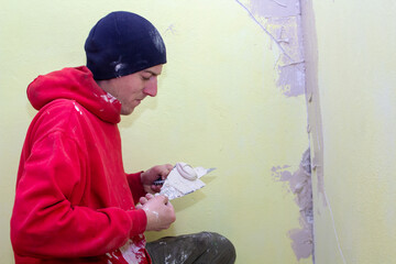 man working with spatulas,work on plastering the walls in the winter in the room