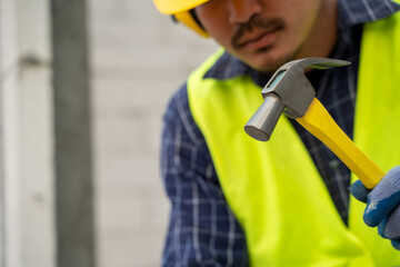 industrial worker building exterior walls in the house under construction,Using hammer for laying bricks in cement.