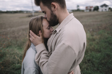 a couple in love walks in an open soybean field in the evening in cloudy weather