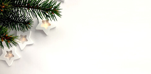 A green spruce branch and a glowing garland of stars on a white background. There is an empty space for text.