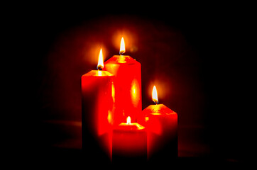 four stylish red advent candles burning on black background