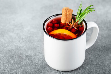 tea with cranberries, cinnamon , orange, rosemary, star anise and honey in a white cup on a gray background