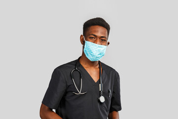 Confident male doctor. Cheerful african doctor in medical mask standing against gray background