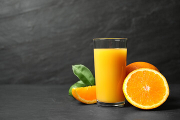 Glass of orange juice and fresh fruits on grey table. Space for text