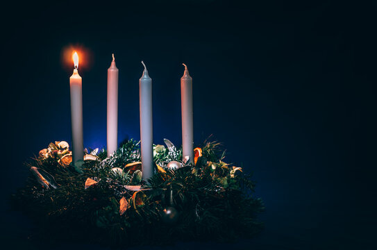 first advent candles burning on black background