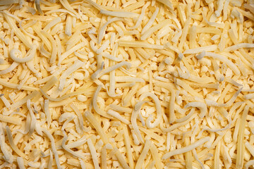 Full frame top view of yellow grated cheese