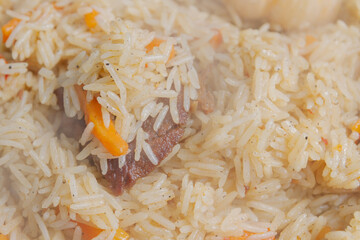 Cooking pilaf in a cauldron on the grill outside in the summer