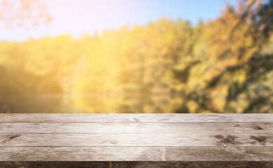 Naklejka na ściany i meble Autumn background, empty old rustic wood table with blur forest trees and sunlight, Autumn fall backdrop, banner for product display advertise online copy space, thanksgiving textured grungy floor.