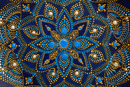 Decorative ceramic plate with black, blue and golden colors, painted plate on background, dot painting