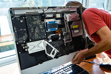 Male computer technician repairing broken silver desktop computer while opening its parts and analysing and understanding problem
