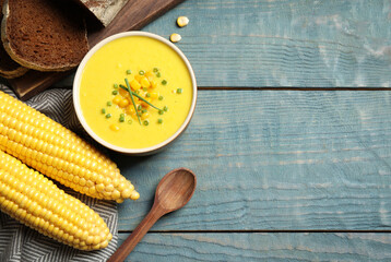 Delicious creamy corn soup served on blue wooden table, flat lay. Space for text