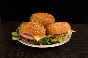 Close-up of a delicious fresh homemade Burger with lettuce, cheese, onion and tomatoes on a dark background