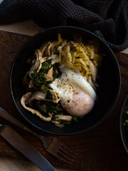 Poached egg and fermented vegetables in black bowl