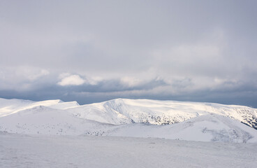 Fototapeta na wymiar Snow-covered mountain peaks under a cloudy sky.