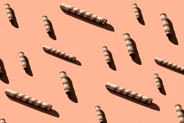 Seamless pattern of waffle tubes of different sizes with hard shadows of trends on a cream background. Minimal sweet food concept