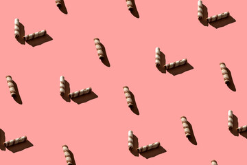 Seamless pattern of waffle tubes of different sizes with hard shadows of trends on a pink background. Minimal sweet food concept