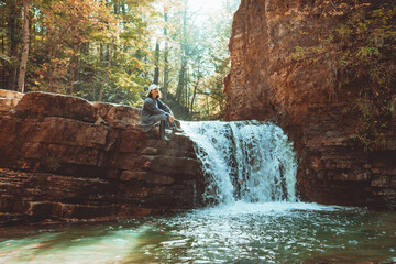 hiker woman enjoying waterfall in autumn forest