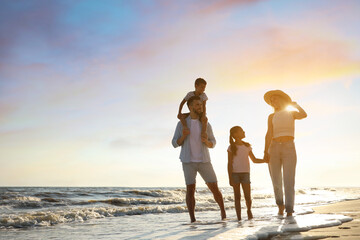 Happy family walking on sandy beach near sea