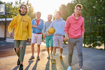 diverse young city boys are ready to play basketball together, sport club members have fun outdoors, in casual wear. portrait