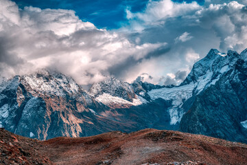 Cascade of mountains with fluffy white clouds and crystal blue sky