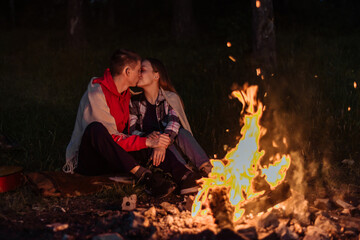 Romantic evening at the campfire and tent. young couple camping on a summer night in the woods