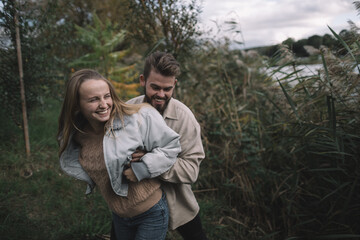 a loving couple stands in the reeds against the backdrop of a lake in the evening and communicates