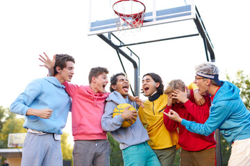 friendly team of young basketball players celebrate the winning in game outdoors, they smile, have...